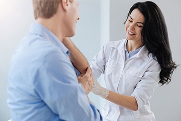 a female dermatologist examines the arm of a male patient