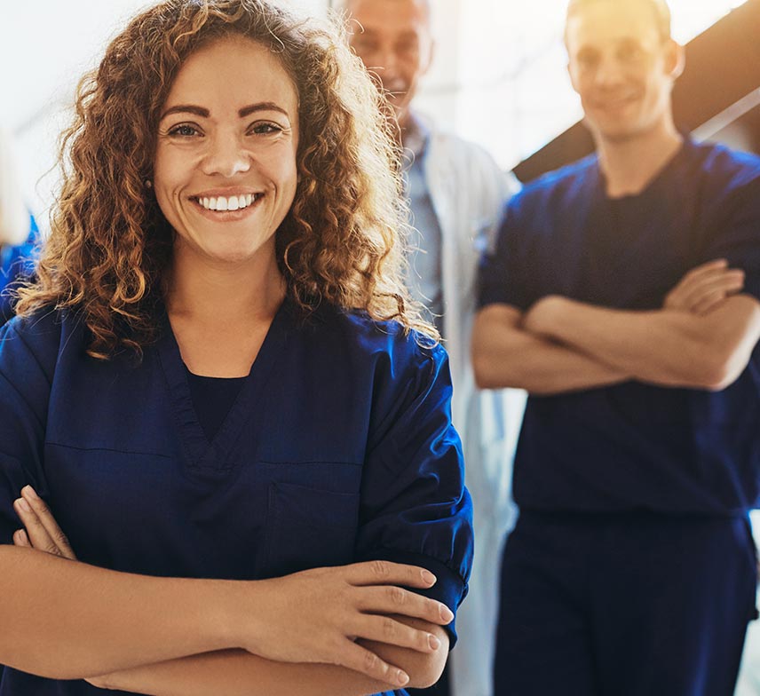 a female dermatologist in dark blue scrubs smiling widely