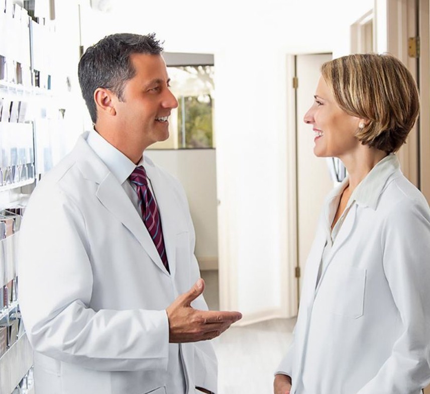 two dermatologists converse in the hallway of a dermatology office
